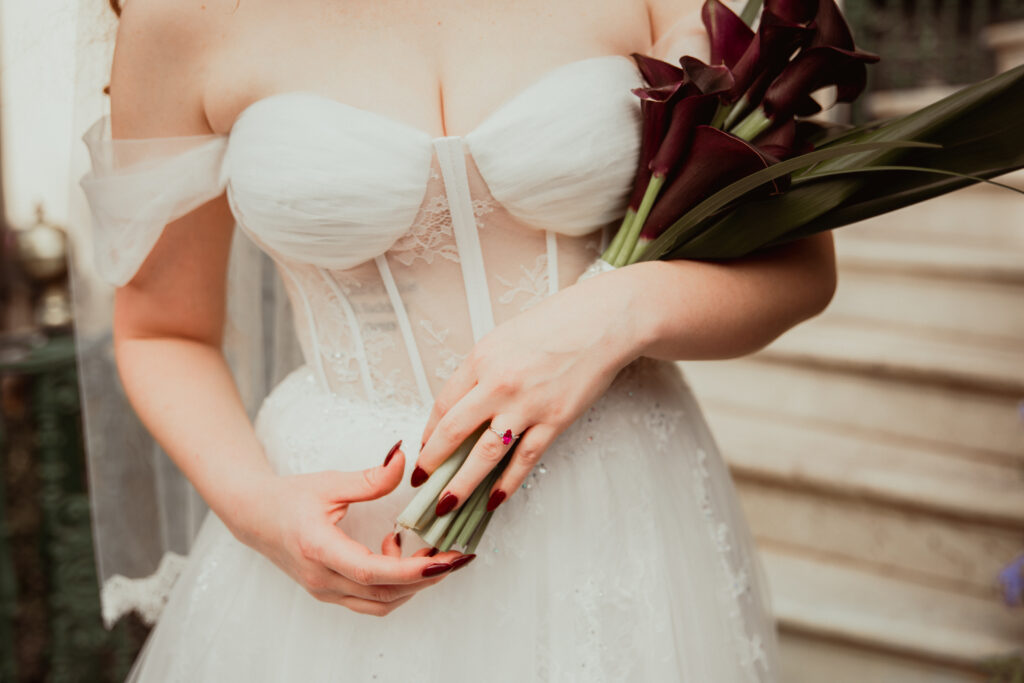 bride holding bouquet showing off her new pink diamond ring