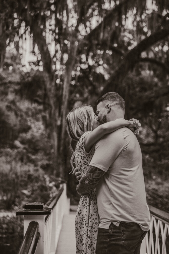 man kissing a woman on a white bridge at Magnolia plantation and gardens