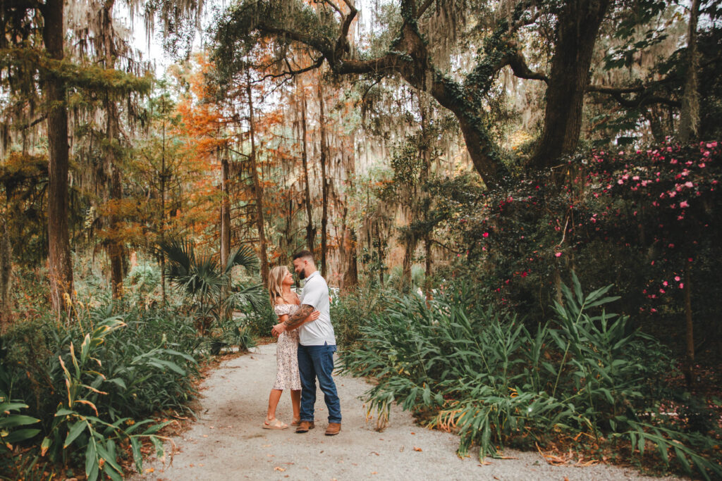 couple looking at each other smiling under oak and cypress trees at magnolia plantation in Charleston SC