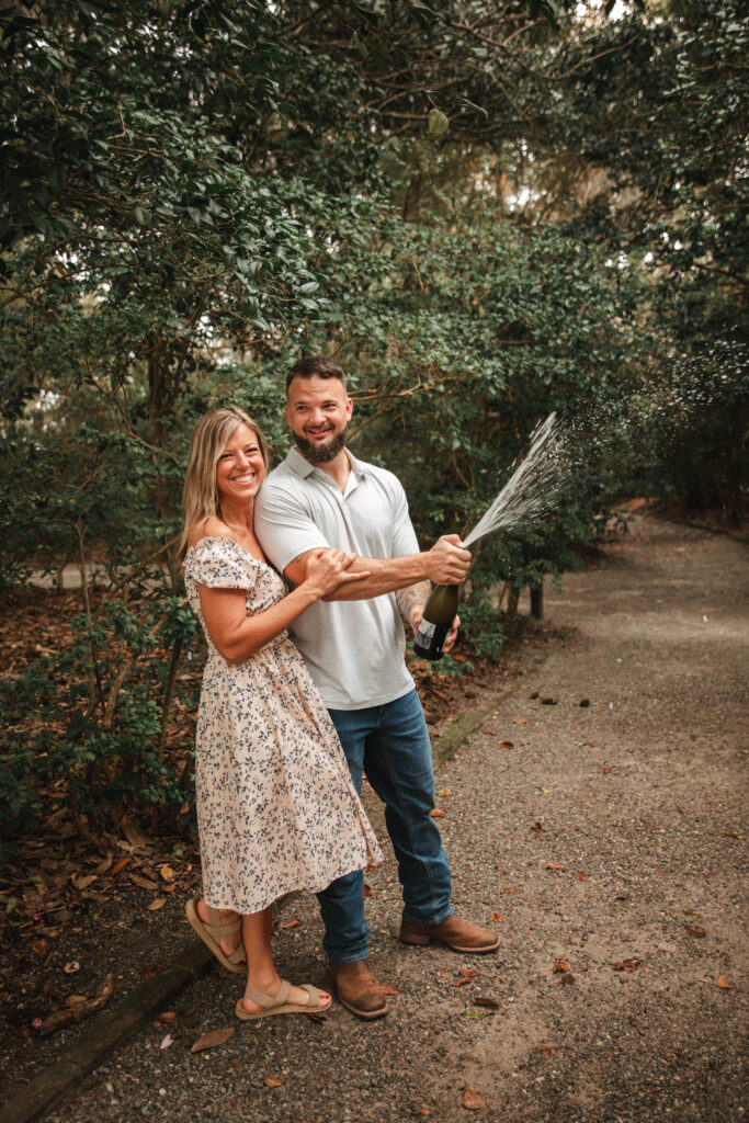 couple smiling while popping a bottle of Champagne at Magnolia plantation and gardens