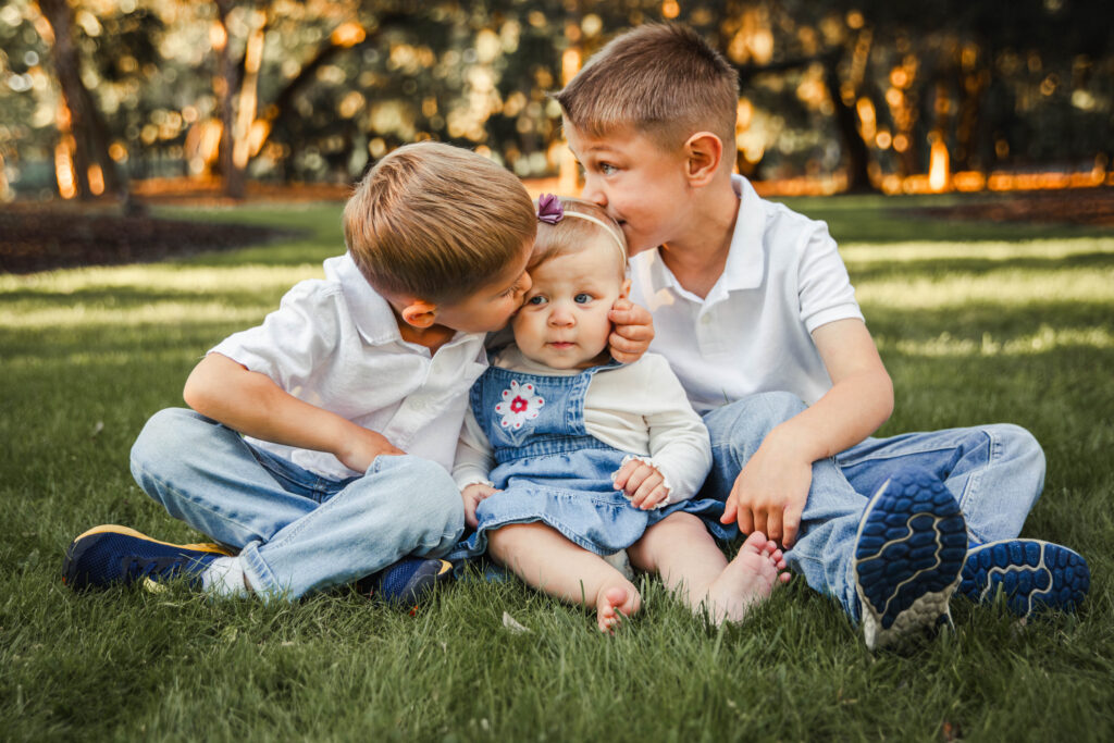 2 little boys kissing their baby sister on the cheek