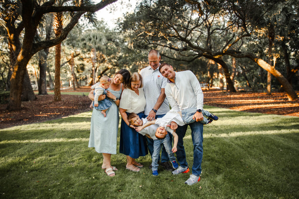 multi-generational family photo with one one the boys being help upside down. 