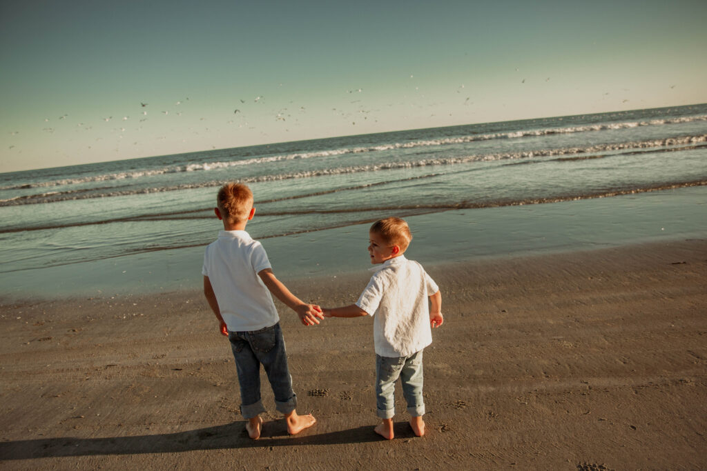 brothers holding hand on the beach in Charleston SC