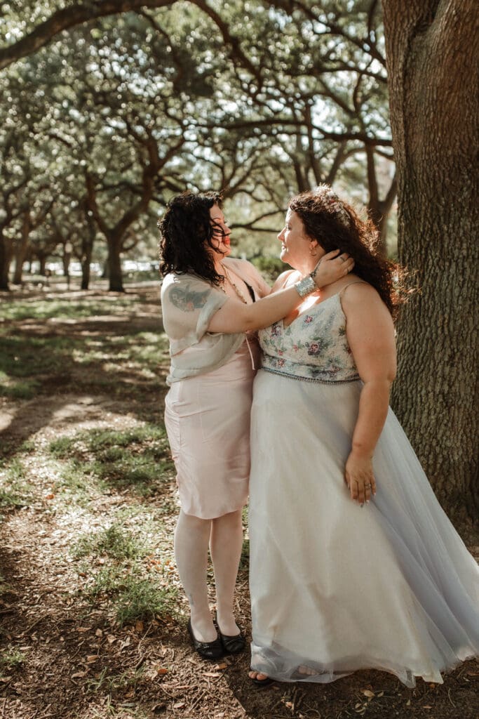 The bride's daughter adjusting a her mother's hair beside an oak tree at White Point Garden.