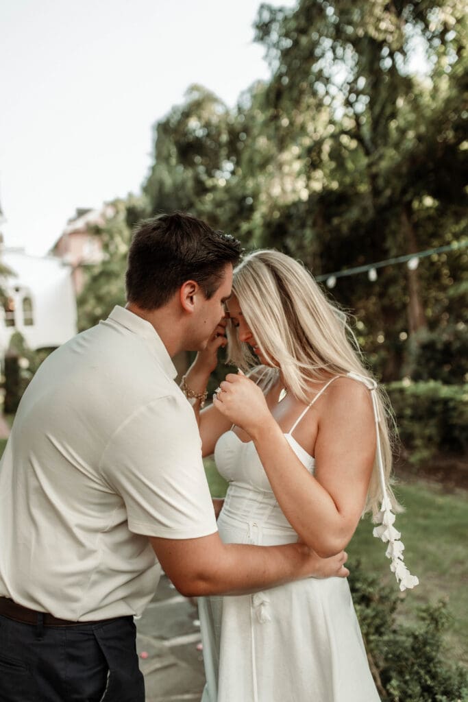 A newly engaged couple touching foreheads and smiling together in the garden.