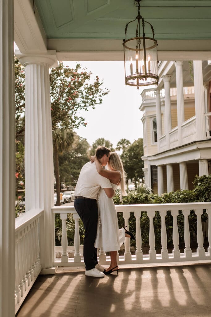 A couple kissing on a sunlit porch beneath a hanging lantern at 20 South Battery.